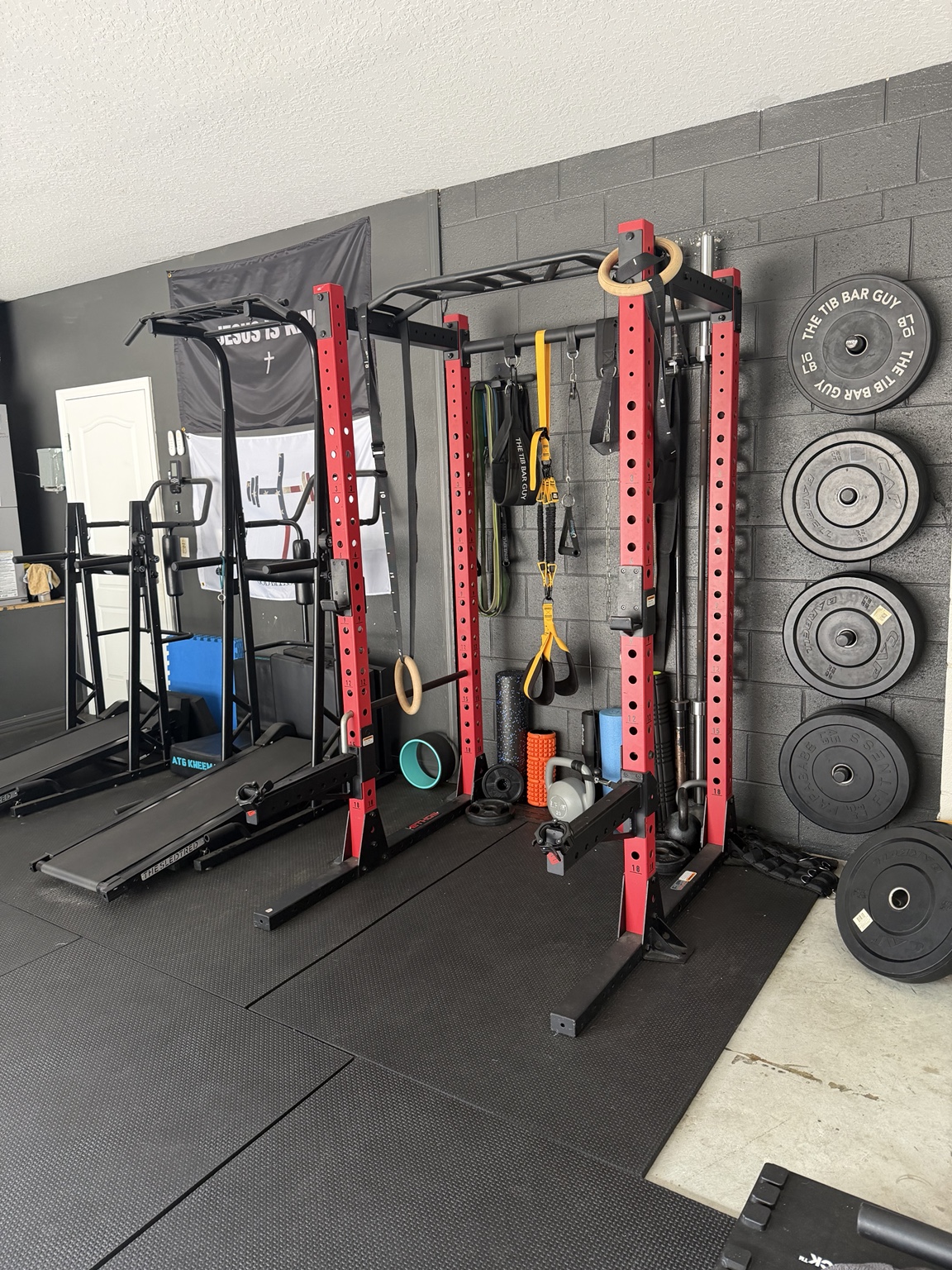 Power rack, rings, resistance bands, weights, and mobility equipment in Nick’s DeLand gym